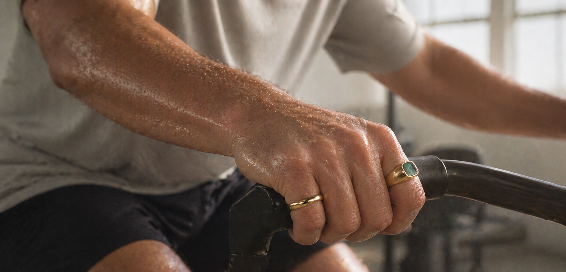 Man on a bike in the gym wearing the plain gold band and the stone ring